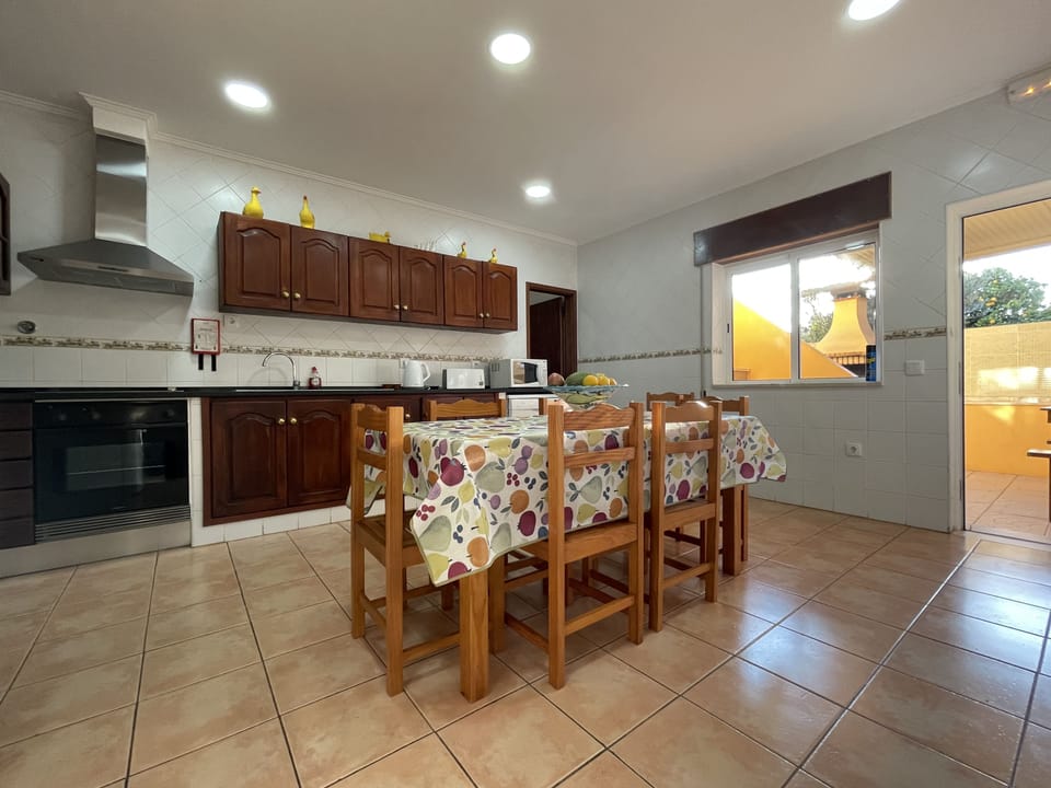 Fully equipped, spacious kitchen with door to outside covered BBQ with long table & chairs, including sink.