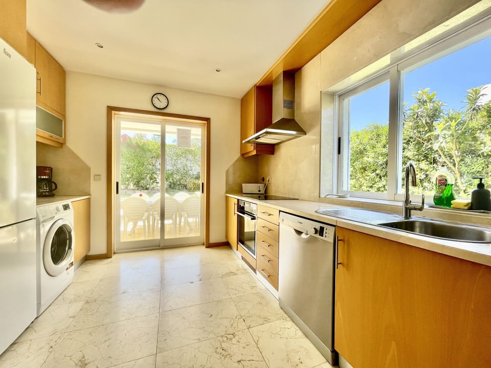 Fully equipped kitchen with sound system, large window facing the side garden & double doors to terrace, pool, lawn & established garden.