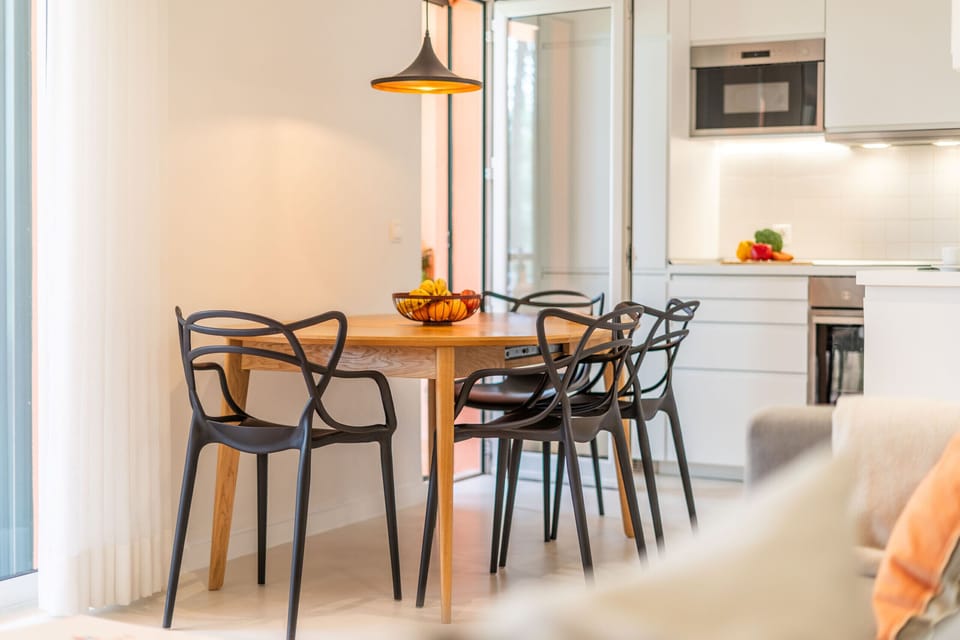 Open-plan dining area with wooden table and black chairs — Apartment Aroeira Golf II, holiday apartment in Portugal