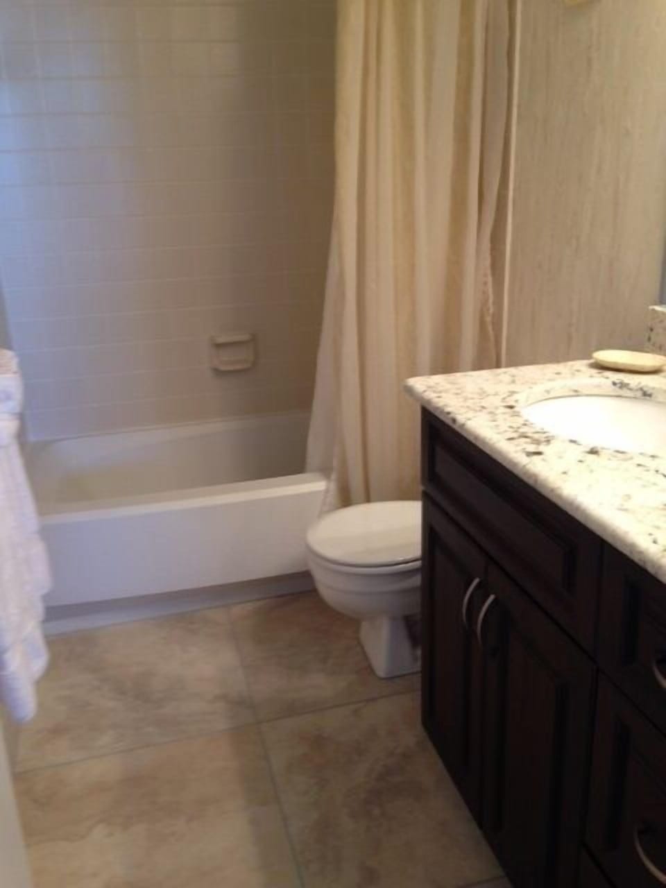 Guest bath w granite counter top on vanity, tile floor, tub and shower combo. 