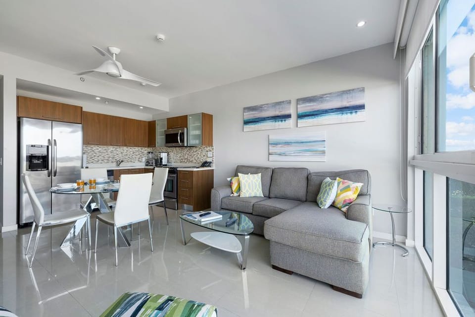 Your bright, modern living space flows seamlessly from kitchen to lounge, with calming coastal art and floor-to-ceiling windows framing stunning views—a perfect retreat after beach days.
