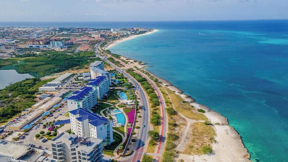 Aerial view showcasing the property's beachfront location along turquoise Caribbean waters, with easy coastal road access and nearby resort amenities.