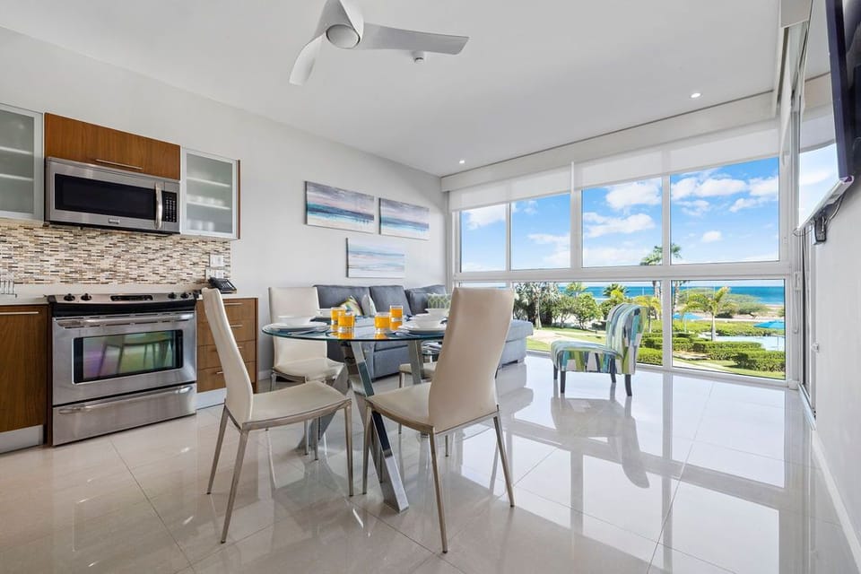Bright, modern living space with a fully equipped kitchen, cozy dining nook, and stunning ocean views through floor-to-ceiling windows—your coastal retreat awaits.