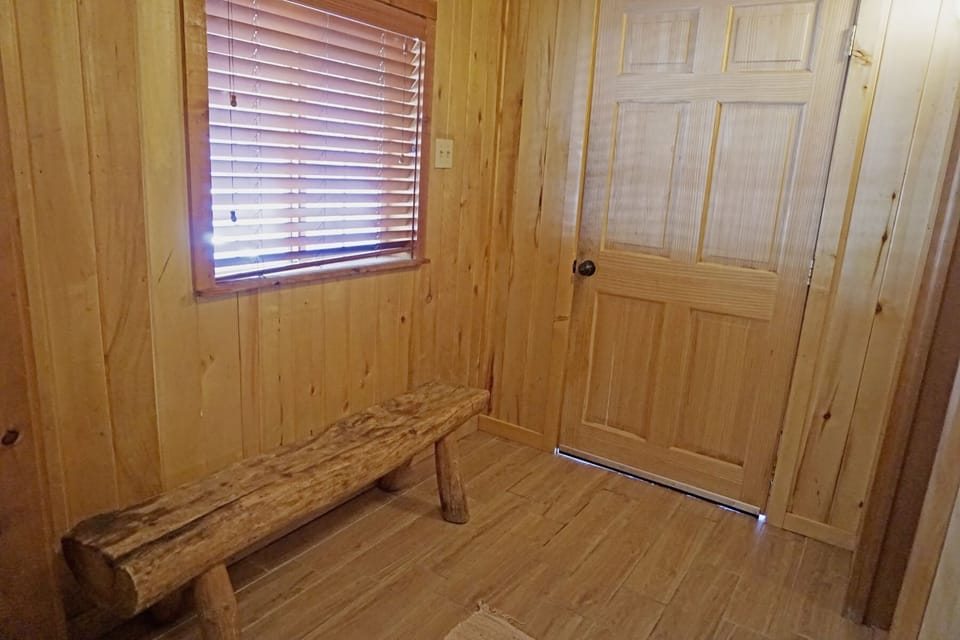 A rustic wooden entryway welcomes you with warm natural tones and simple charm, featuring a handcrafted bench perfect for setting down your bags.