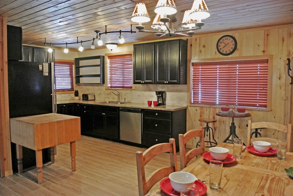 You'll love preparing meals in this rustic cabin-style kitchen with modern appliances, warm wood accents, and a cozy dining table set for memorable gatherings with family and friends.