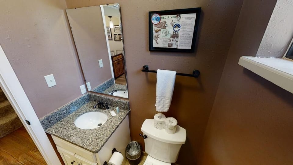 Your private bathroom features a granite vanity, fresh towels, and thoughtful touches like spare toilet paper and a small trash bin—everything you need for a comfortable stay.