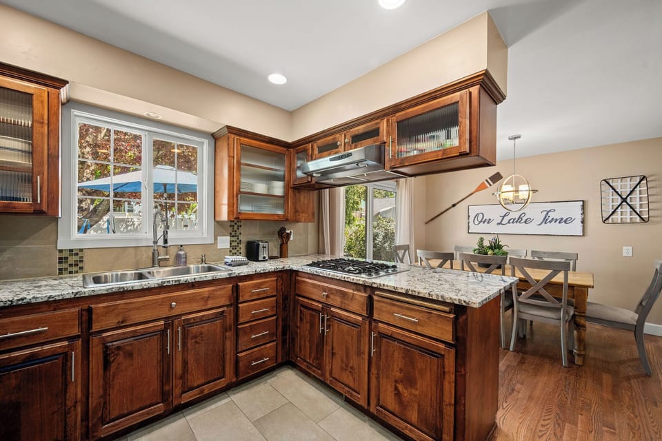 Gather in this fully equipped kitchen with rich wood cabinetry, granite counters, and modern appliances—perfect for preparing your favorite meals while lake views peek through the windows.