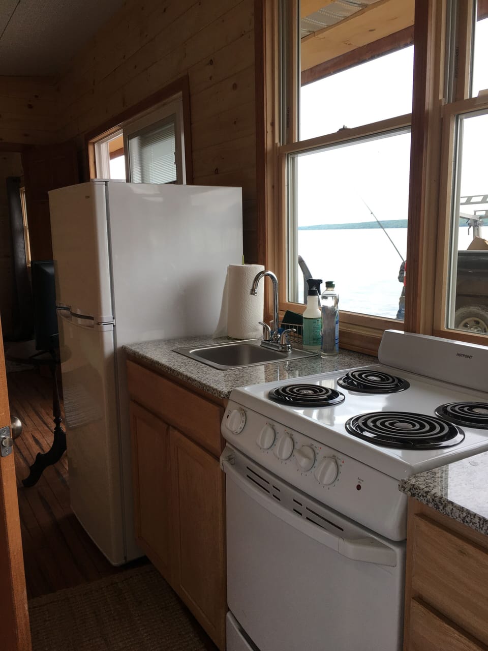 Kitchen has refrigerator, oven/stove, pots, pans, dishes, silverware, glasses. 