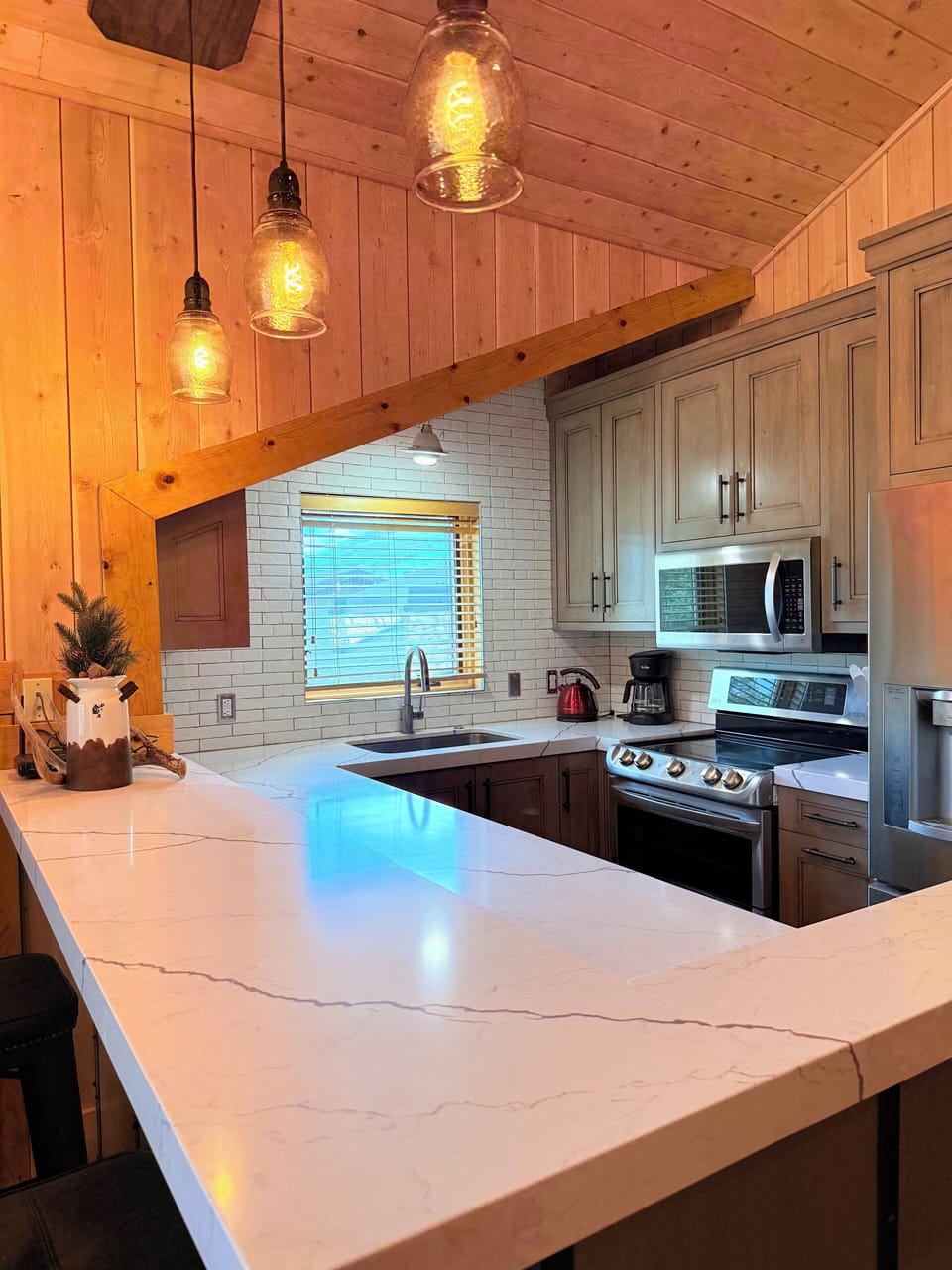 Fully-equipped kitchen with all appliances, bar stools at counter