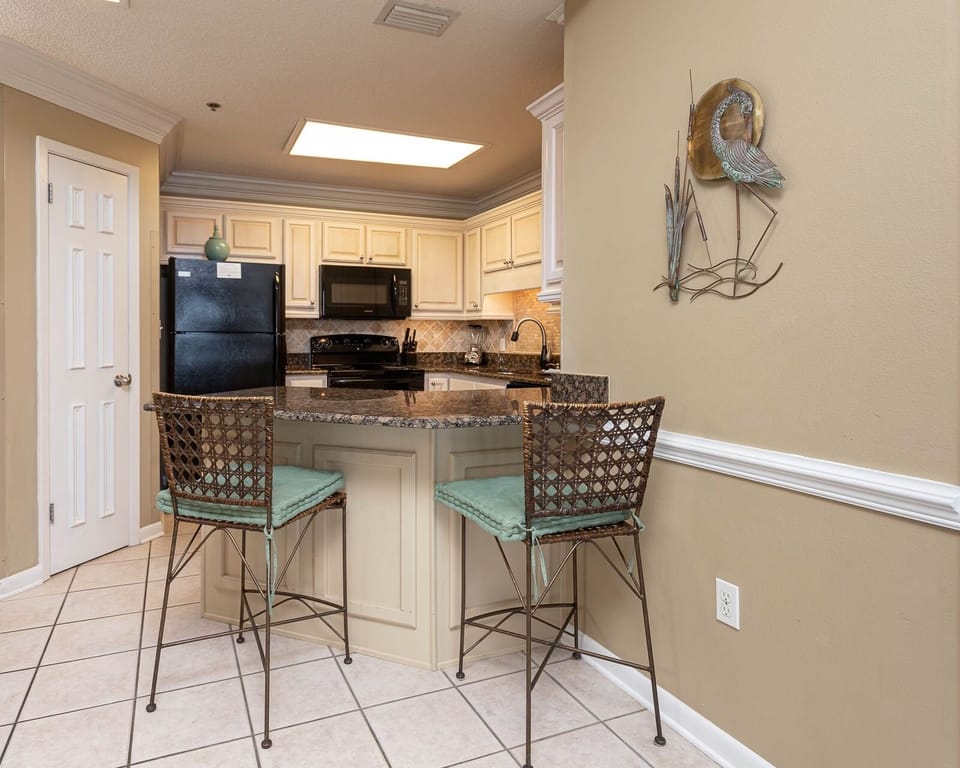 Kitchen area features a granite breakfast bar with stylish seating, complemented by light cabinetry and decorative accents