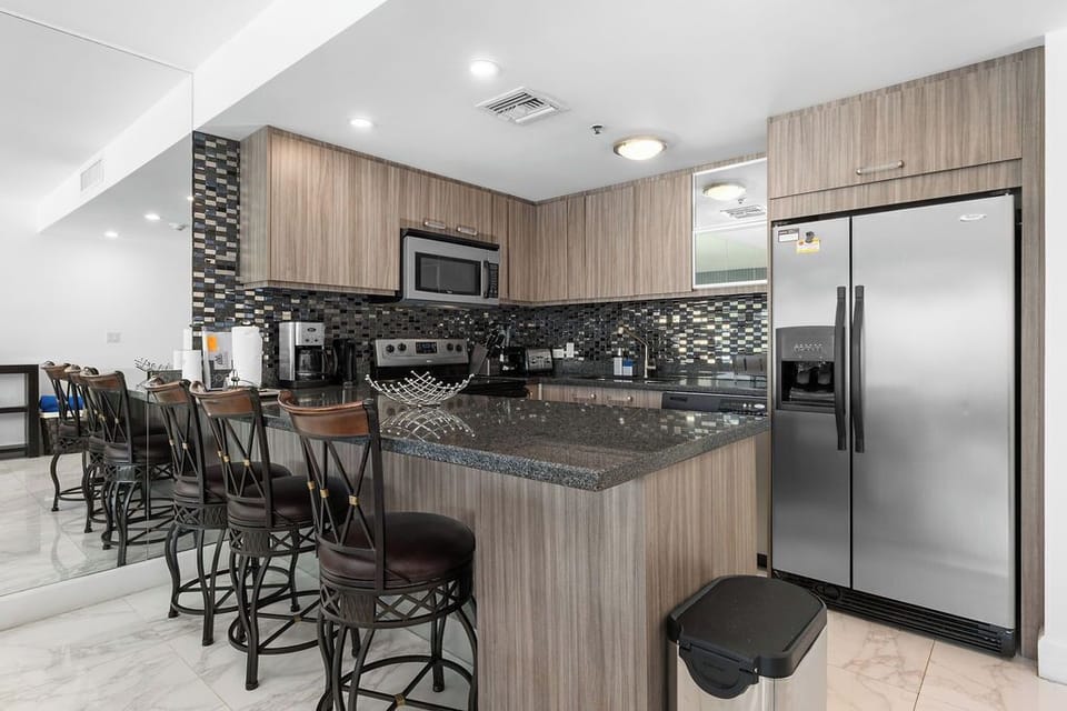 Step into your fully equipped kitchen featuring sleek granite countertops, stainless steel appliances, and stylish bar seating—perfect for casual meals or morning coffee while planning your daily adventures.
