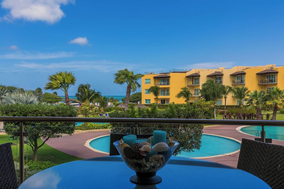 Sip your morning coffee from your private balcony, overlooking turquoise pools, lush palms, and ocean views beyond—pure tropical paradise.