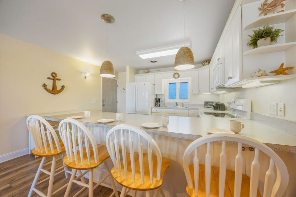 Your coastal kitchen awaits with charming nautical touches and breakfast bar seating for memorable mornings together.