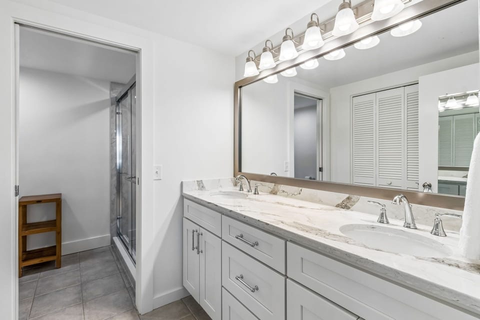 Master Bathroom with Double Sinks, Quartz Countertops, and a Tiled Walk In Shower