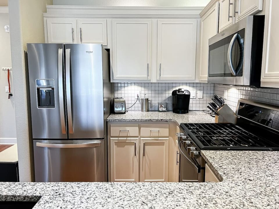 Cook with ease in this sleek and modern kitchen, equipped with stainless steel appliances, granite countertops, and a full suite of essentials for your culinary needs. Perfect for preparing meals during your stay