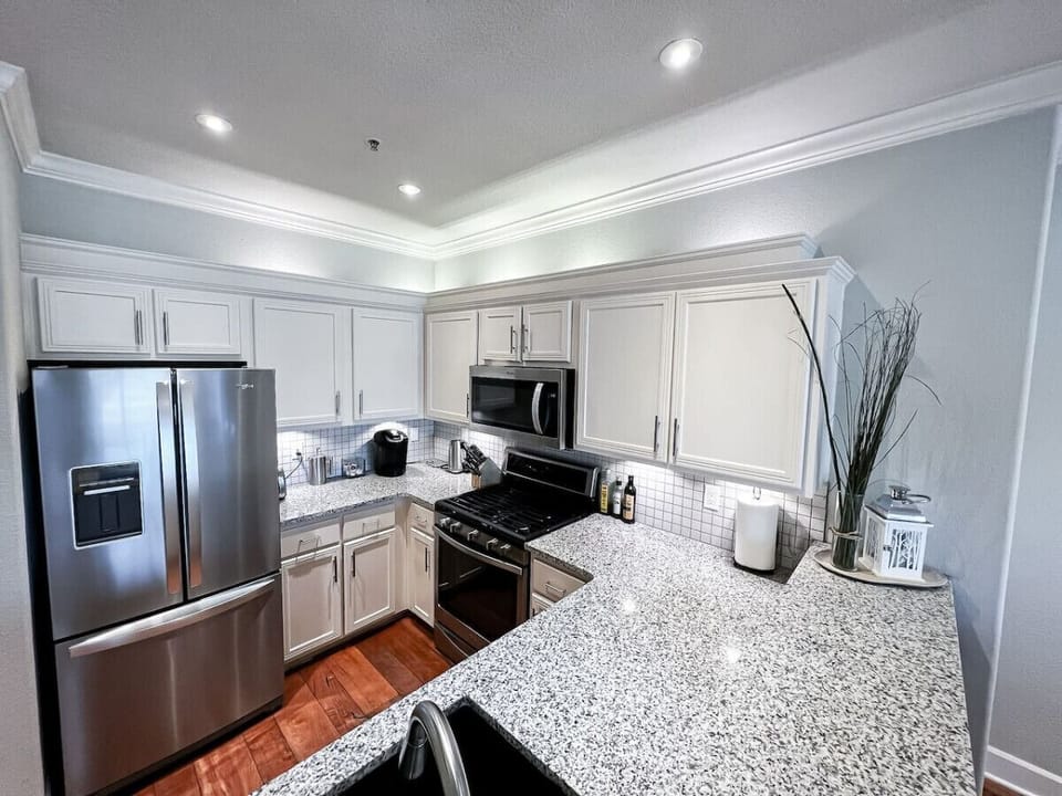 Cook and entertain in this modern kitchen featuring expansive granite countertops, stainless steel appliances, and ample cabinet space. A perfect blend of style and functionality for your stay