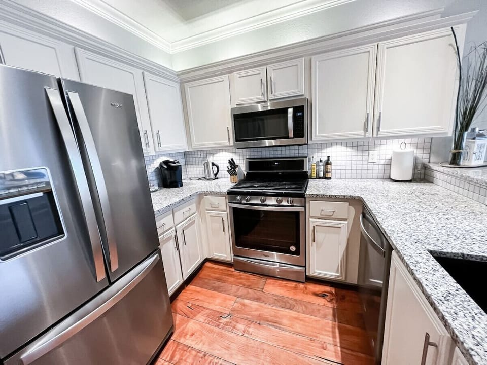 Prepare meals with ease in this beautifully designed kitchen, featuring stainless steel appliances, a spacious fridge, granite countertops, and all the essentials for cooking and dining during your stay