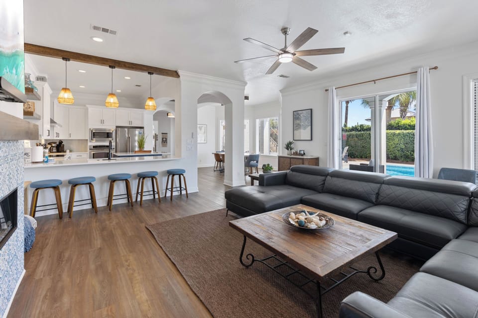 Relax in your open-concept haven where sleek kitchen flows into comfortable living space, complete with pool views through floor-to-ceiling windows.