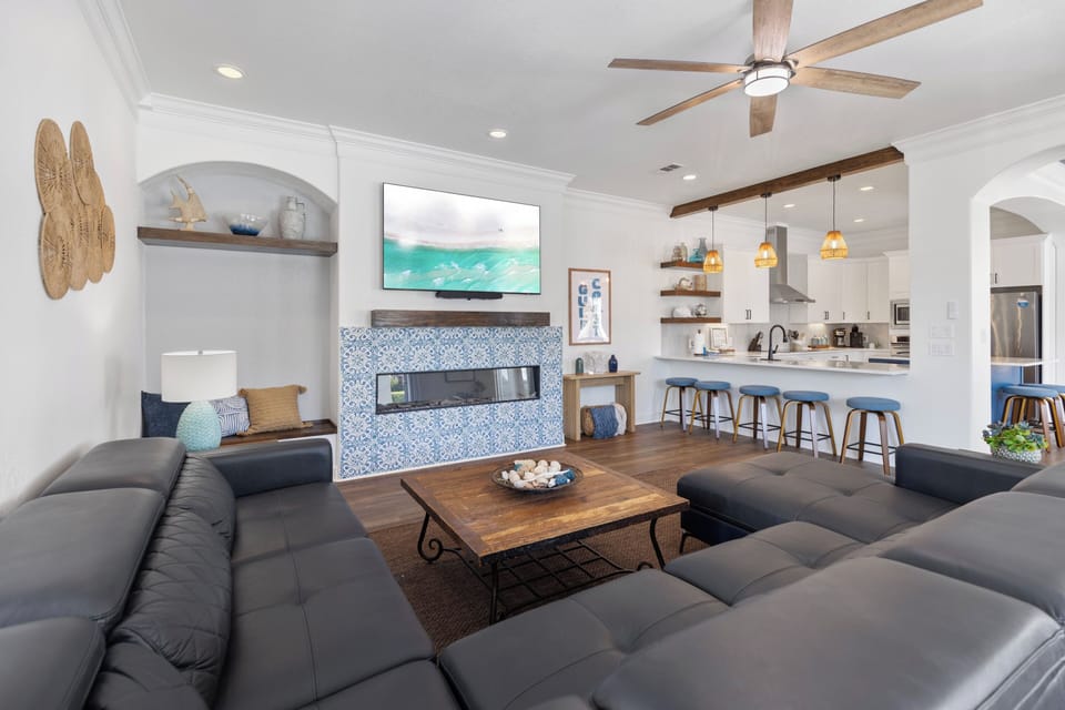 Sink into plush sectional seating where coastal charm meets modern comfort. Your open-concept retreat features a stunning tiled fireplace and seamless kitchen flow.