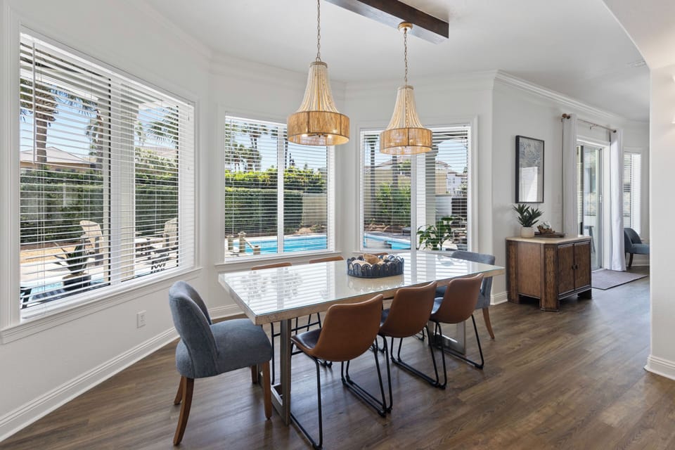 Gather around this stunning dining table where elegant wicker chandeliers cast warm light over your meals while you enjoy pool views.