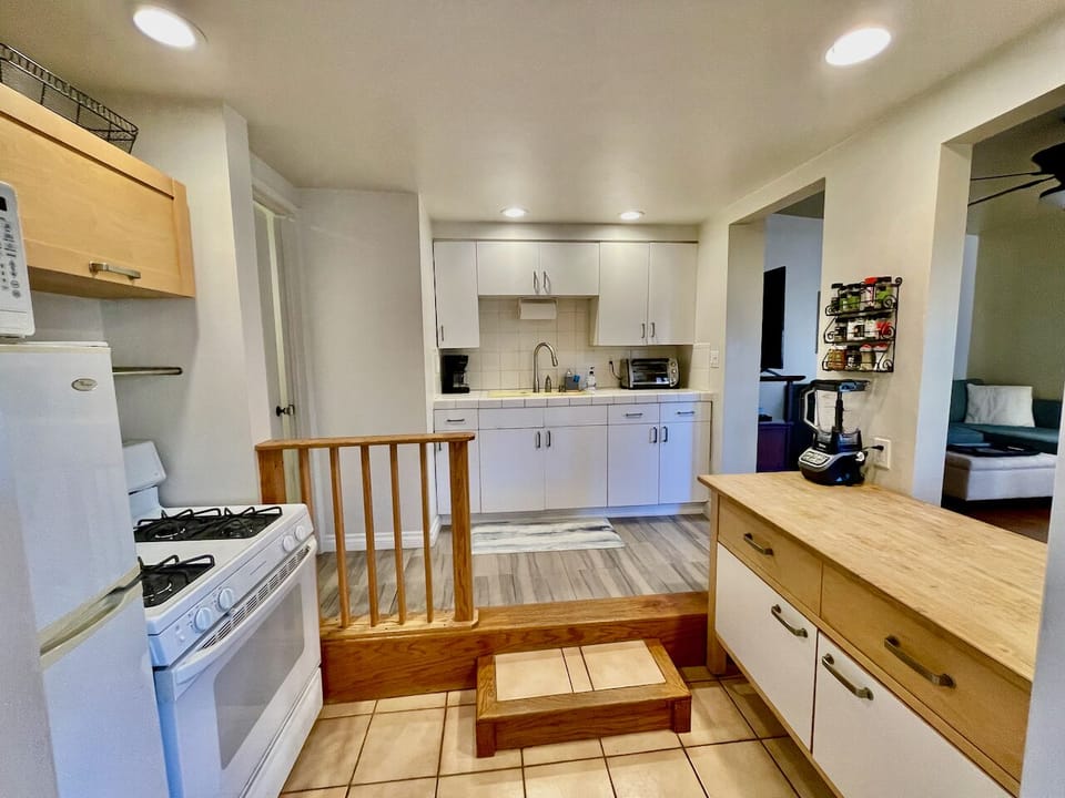 View of the kitchen from the bedroom.  The kitchen island is on the right.  The refrigerator, microwave and stove on the left and the sink straight ahead.