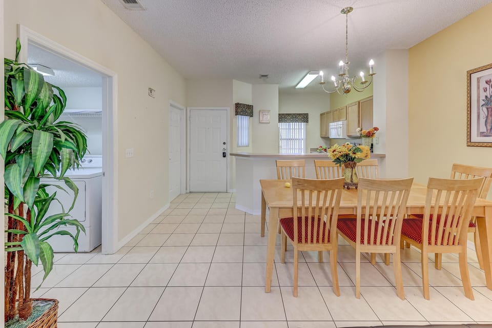 Tile flooring extends through the dining area featuring wooden chairs with red cushions and a floral centerpiece.