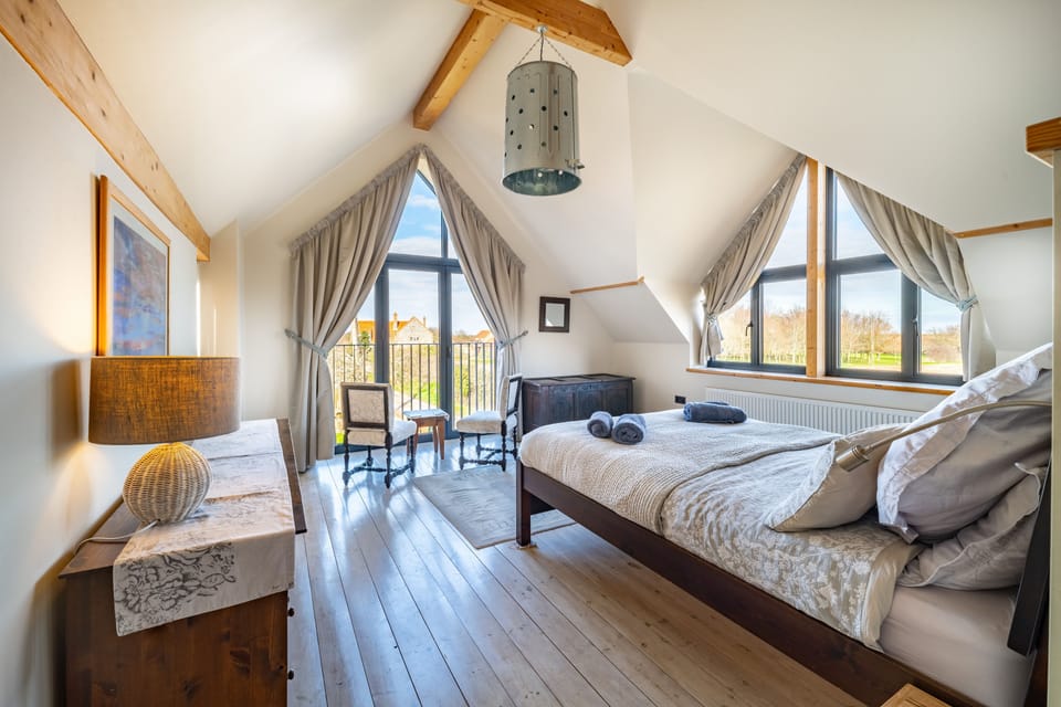 Plumtrees, Thornham: Master bedroom with feature arch windows looking towards Titchwell Nature Reserve and Brancaster Golf Club
