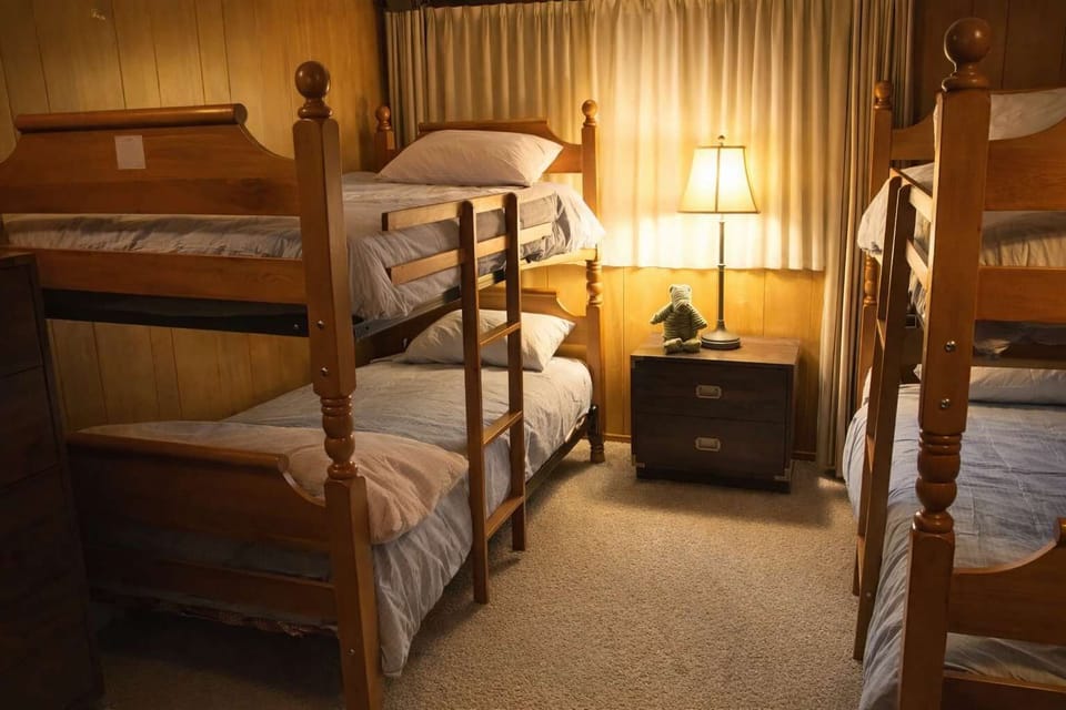 Cozy bunk room with sturdy wooden bunk beds, soft lighting, and comfortable bedding—perfect for kids or group stays.
