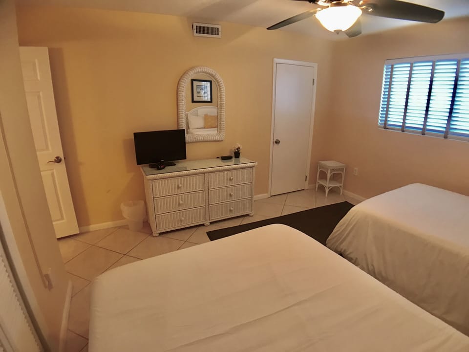 Guest bedroom with two double beds and  TV. 