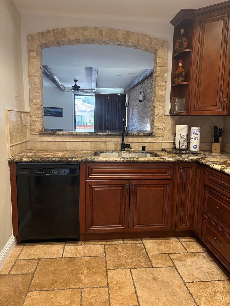 Your gourmet kitchen features rich wood cabinetry, gleaming granite countertops, and a charming stone archway that frames views into the adjacent living space—perfect for preparing meals while staying connected with everyone.