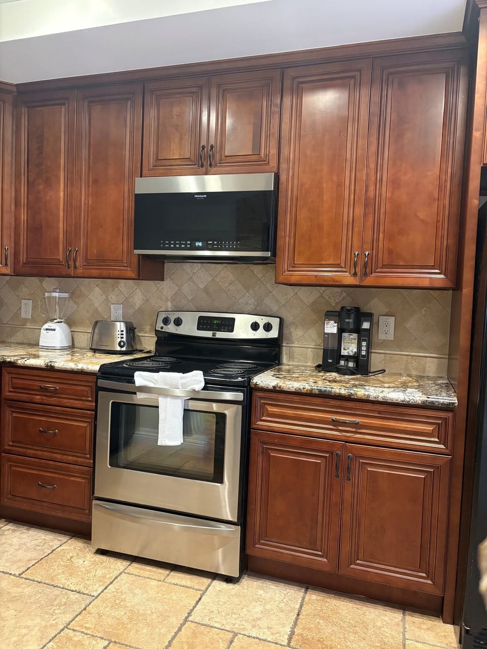 Your fully equipped kitchen features warm wood cabinetry, granite counters, and all the essentials—including a coffee maker ready for your morning brew.
