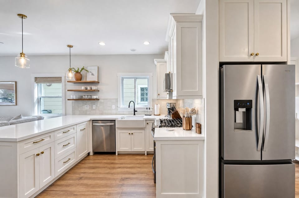 Picture yourself preparing meals in this bright, fully-equipped kitchen featuring stainless steel appliances, open shelving, and plenty of counter space for cooking together.