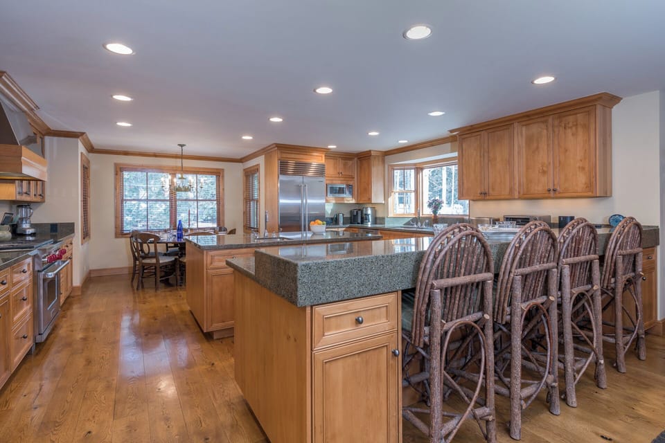 Your spacious kitchen invites culinary adventures with granite counters, rustic bar seating, and warm wood cabinetry bathed in natural light.