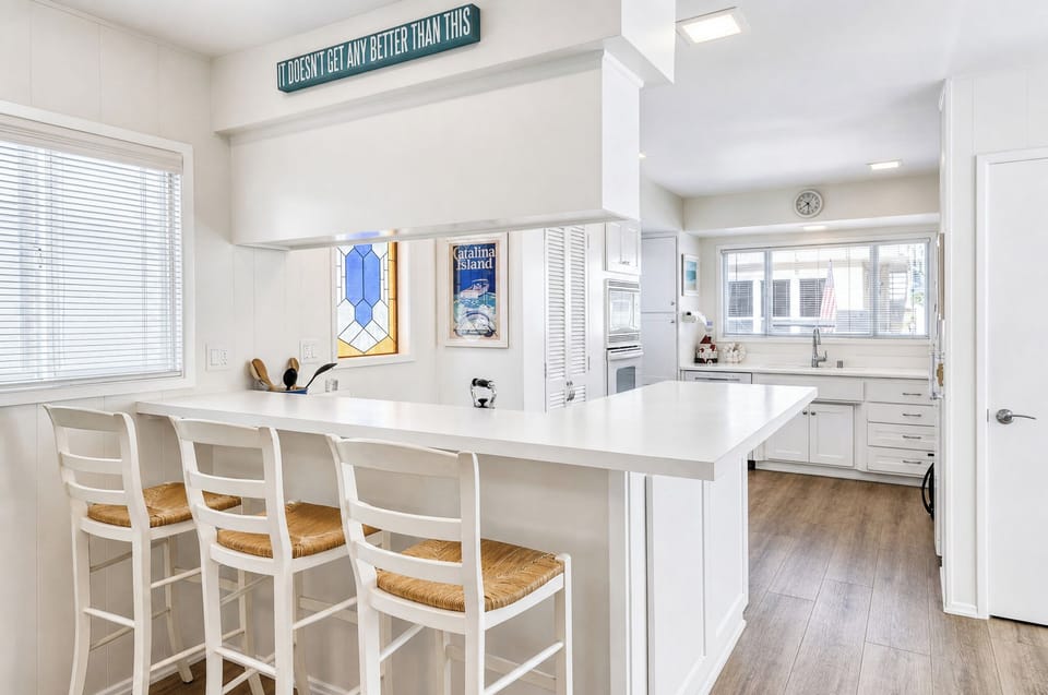 Gather at this inviting breakfast bar where coastal charm meets effortless entertaining. The open-concept design connects kitchen to dining, perfect for morning coffee or lively conversations.