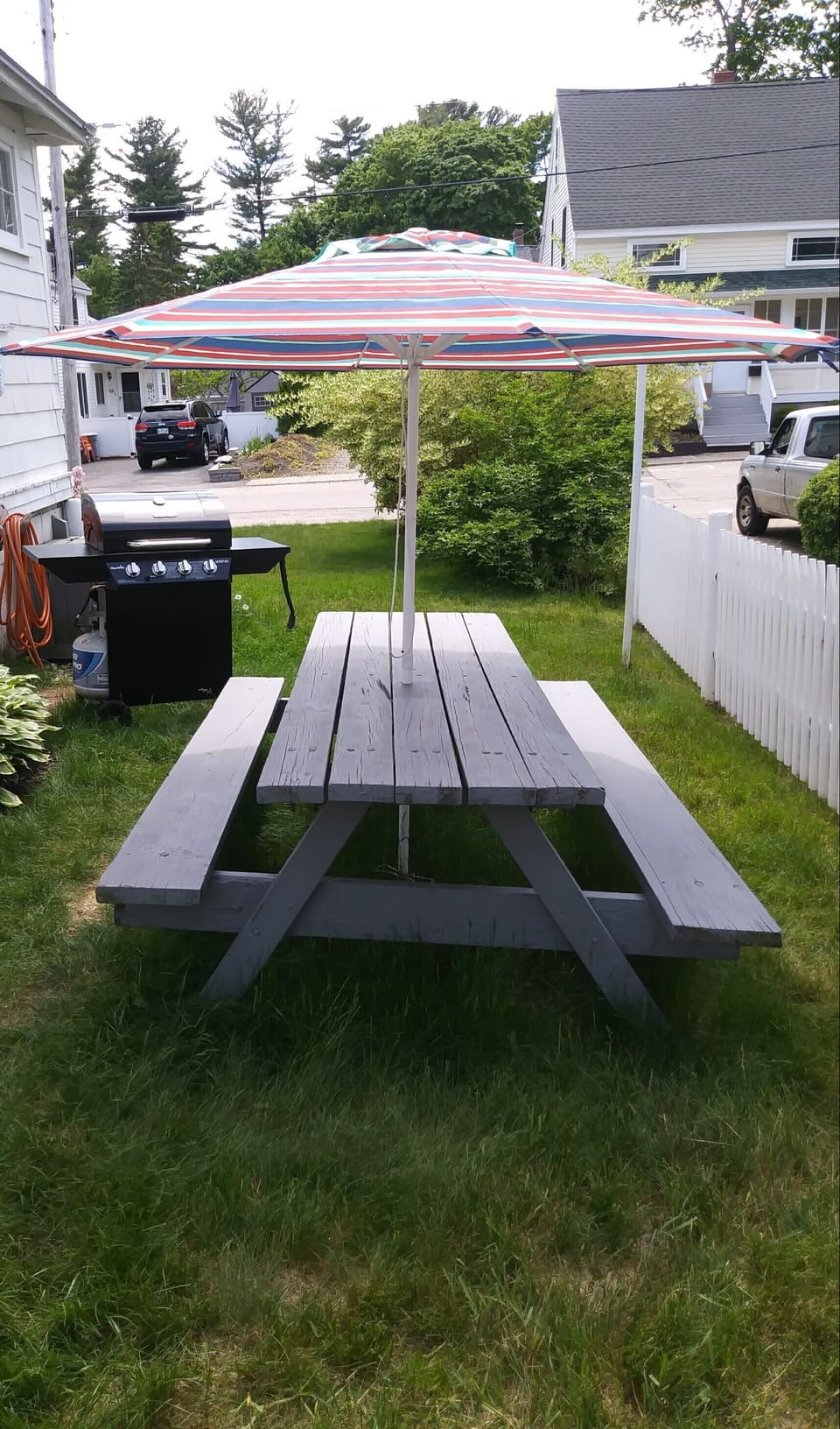 Side yard picnic table, gas grill, clothes line, deck box with beach supplies.