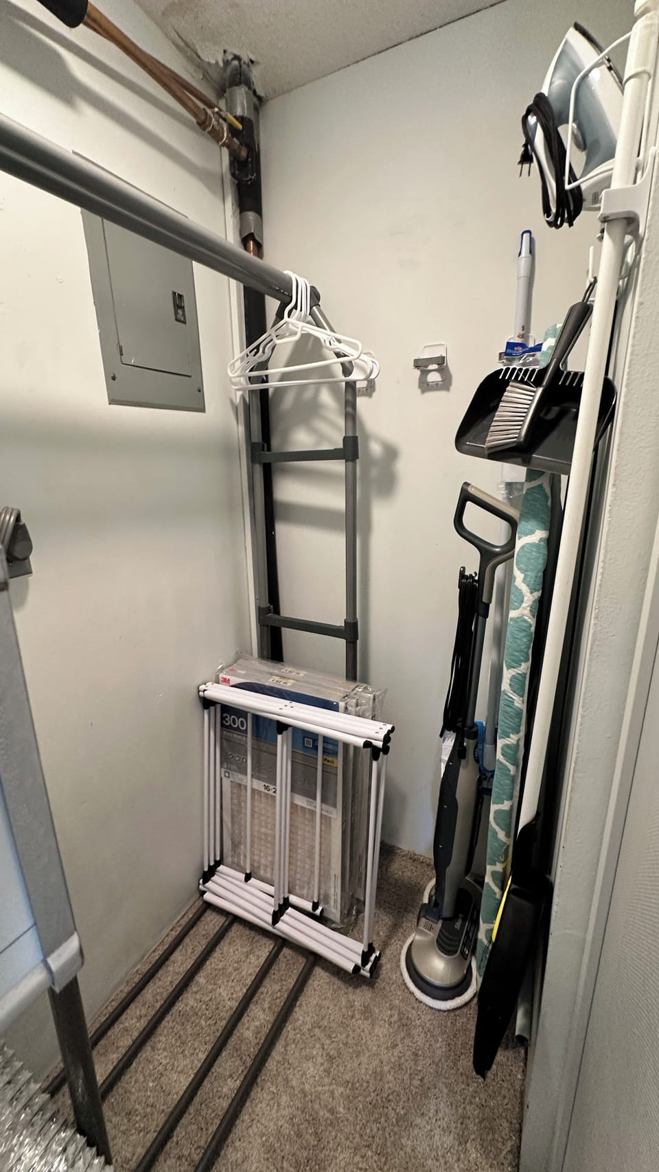 Utility closet with drying rack, vacuum, iron, mop, and broom are for guest use.
