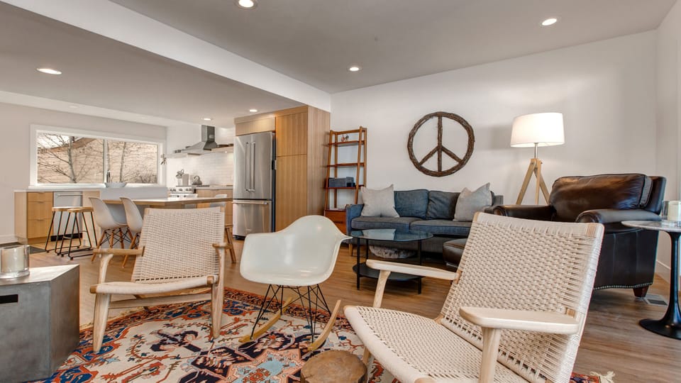 Unwind in our chic open-concept living area, featuring a comfortable sofa, modern kitchen access, and a unique peace sign. It's the perfect spot to relax.