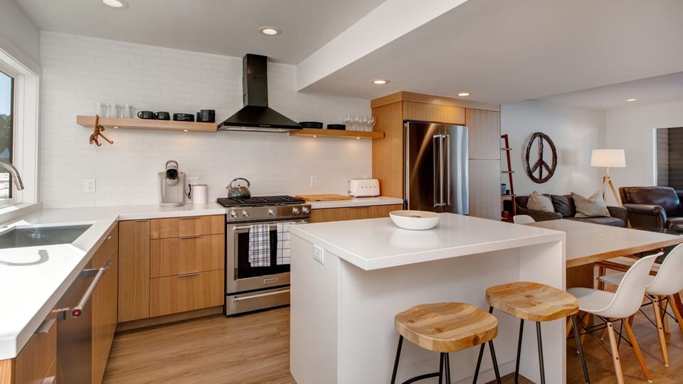 Prepare meals in our fully equipped kitchen, featuring a large island with bar seating, modern stainless steel appliances, and a stylish two-tone design.