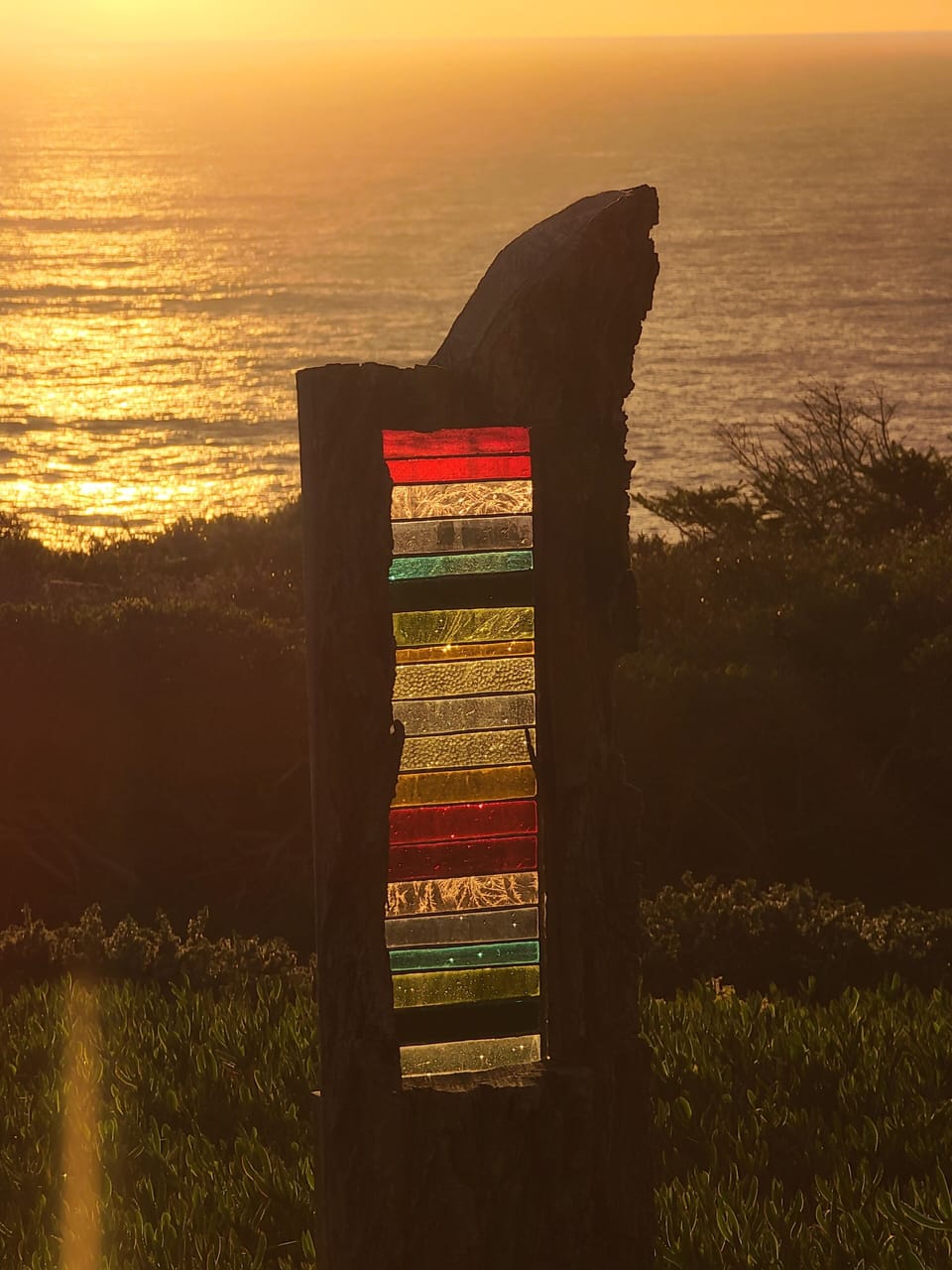 Stained glass set into wood slab catches sunset.