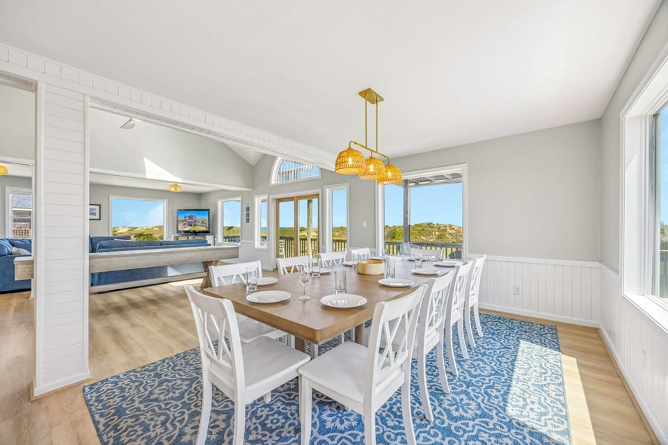 Gather around this elegant dining table while taking in stunning views through expansive windows that frame the natural landscape beyond.
