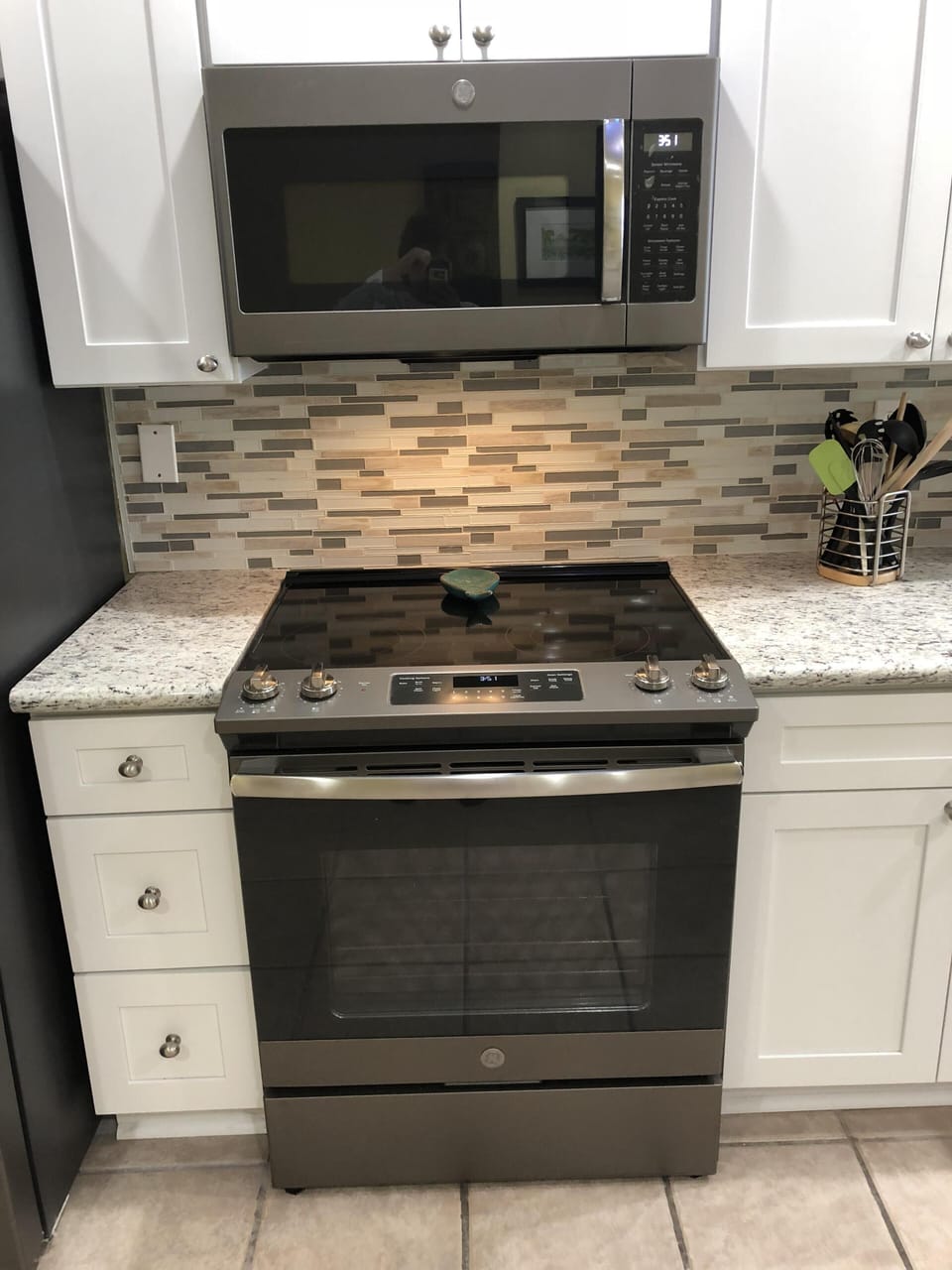 Glass stove top with granite countertops outlined with a glass backsplash.  