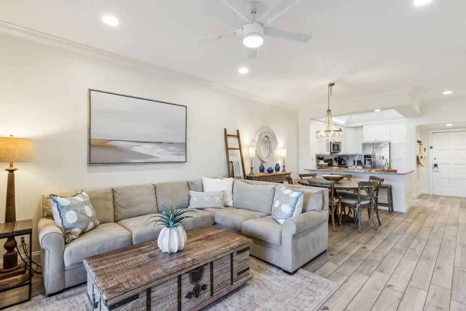 Living Area with a Tan Sectional Positioned around a Large Flat Screen Smart TV and Electric Fireplace