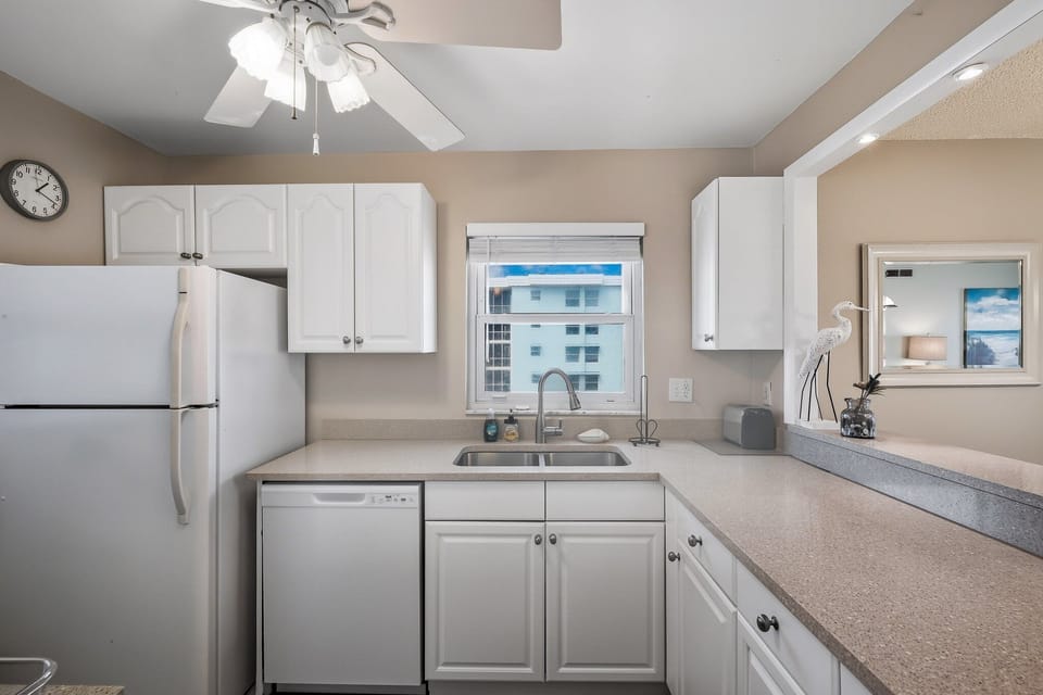 This corner condo features a kitchen with a serene poolside view, blending convenience and tranquility for the perfect beach retreat