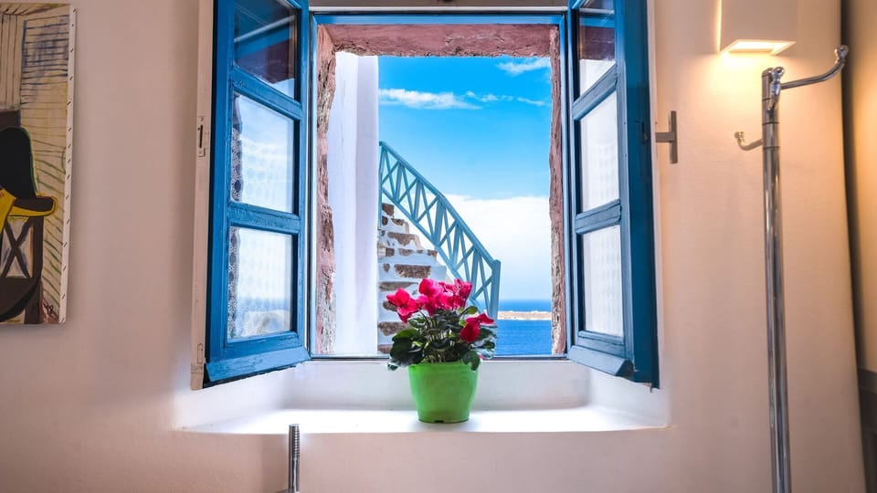 HELIOS's blue shutters open to Santorini serenity and sunset and sea views.