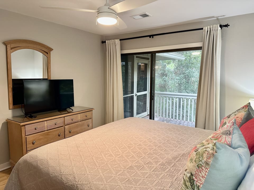 Main bedroom with ceiling fan, TV, and access to deck, 
