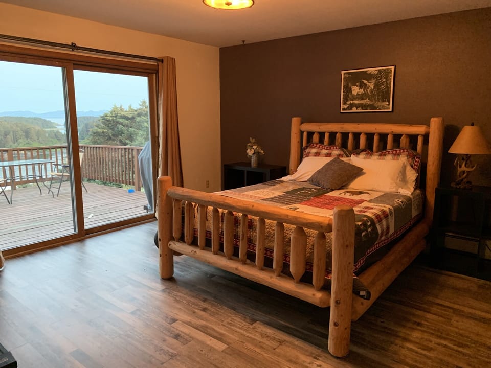 master bedroom with log bed, private bathroom, and deck overlooking channel

