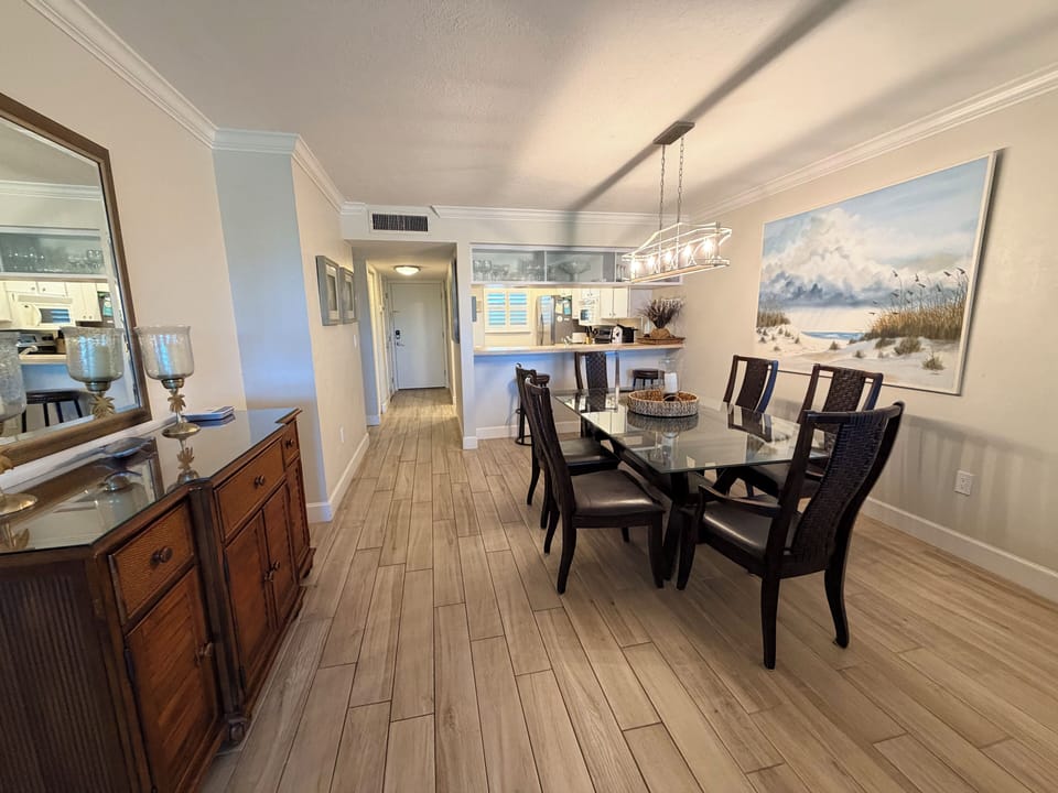 Gather around this elegant dining table where your morning coffee or evening meal feels effortlessly refined, with coastal artwork setting a serene backdrop for your stay.