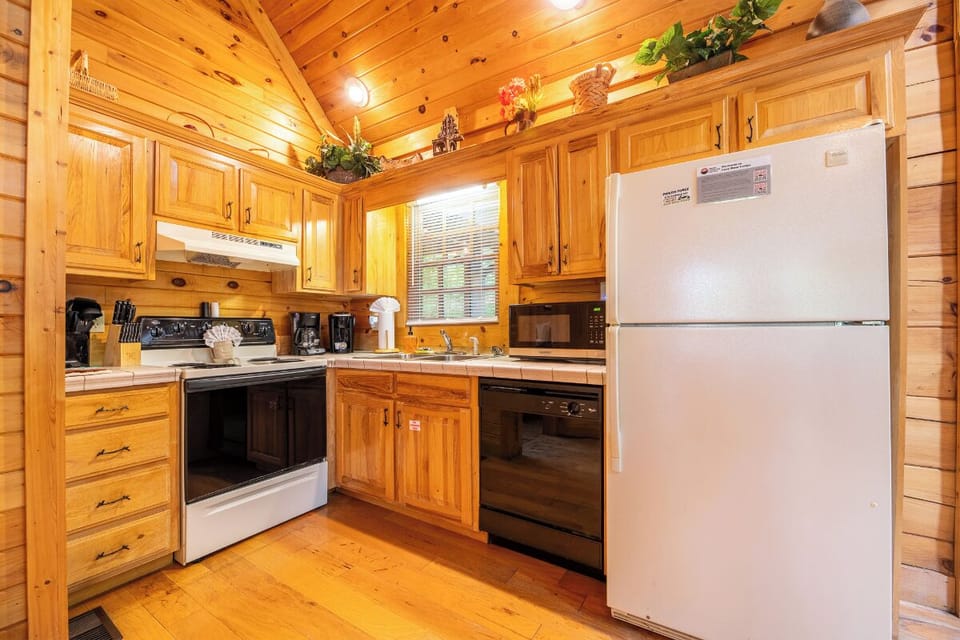 Step into a welcoming cabin kitchen with warm wood cabinetry, full appliances, and vaulted ceilings. Everything you need to cook, relax, and feel at home during your mountain getaway.
