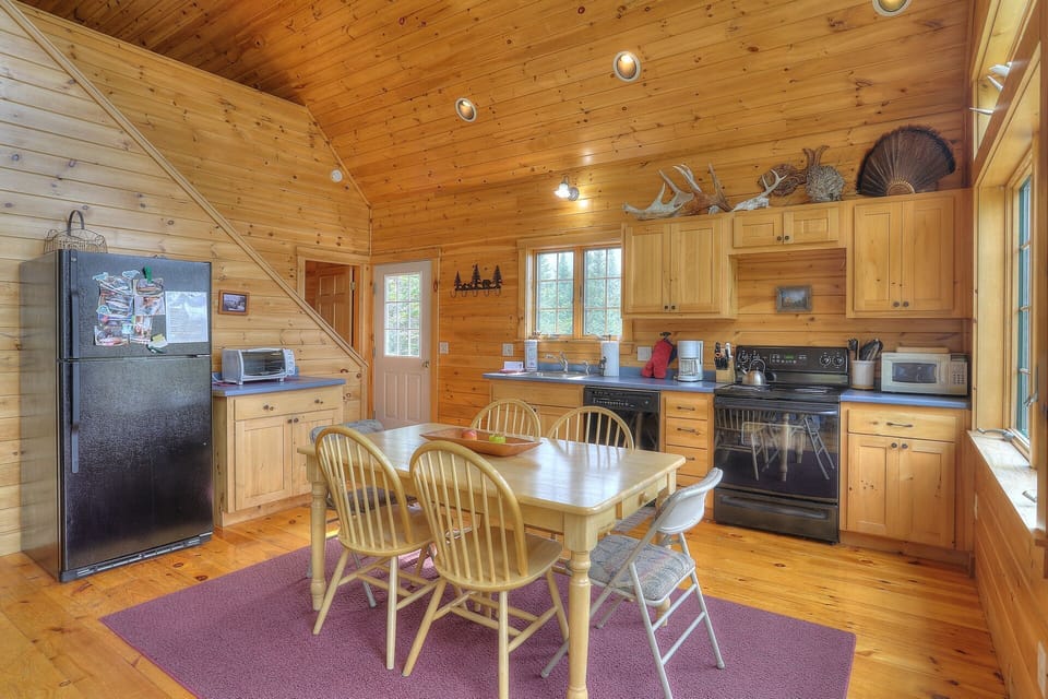 View of kitchen, dining area, and front door from living room
