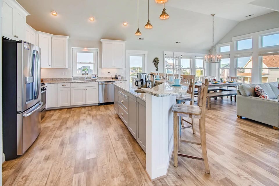 Meal prep is enjoyable in the open kitchen featuring modern, stainless steel appliances including gas stove and French door refrigerator, and a prep sink at the breakfast bar.
